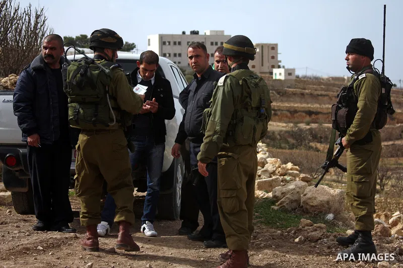 Israeli soldiers stand guard during a demonstration by Palestinian, Israeli and foreign activists against the demolishing of farm land to be used in the construction of Jewish settlements near the existing Israeli settle...