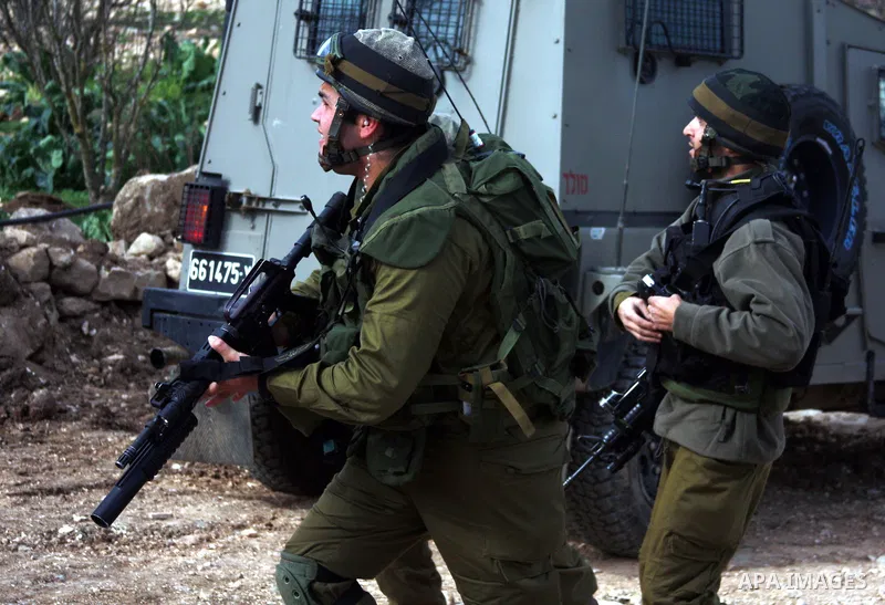 Israeli soldiers stand guard during a demonstration by Palestinian, Israeli and foreign activists against the demolishing of farm land to be used in the construction of Jewish settlements near the existing Israeli settle...