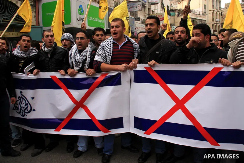Palestinians hold Al-Jazeera logos printed in an Israeli flag during a rally in the West Bank City of Nablus , to protest against Al-Jazeera TV Channel on 27 January 2011. Al-Jazeera, a Qatar-based Arab satellite station...