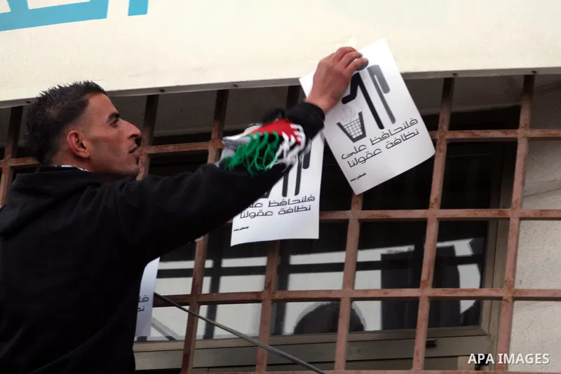 A Palestinian youth pastes placards denouncing Al-Jazeera during a protest near the offices of the pan-Arab news channel in the West Bank city of Ramallah on January 27, 2011. Al-Jazeera, a Qatar-based Arab satellite sta...