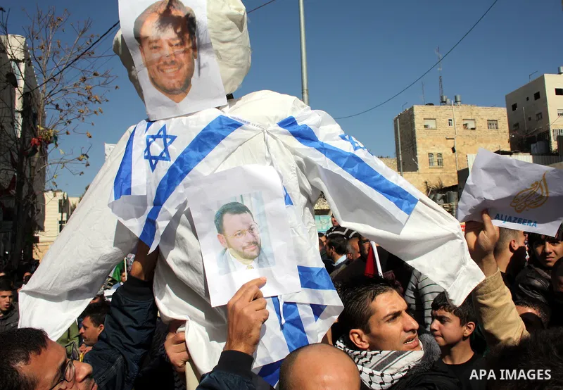 Palestinian Fatah supporters hold flags and signs during a rally supporting Palestinian President Mahmoud Abbas, and against Al-Jazeera, in the West Bank town of Hebron, Friday, Jan. 28, 2011. Al-Jazeera, a Qatar-based A...