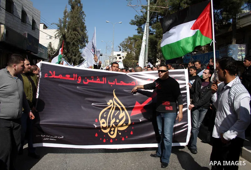 Palestinian Fatah supporters hold flags and signs during a rally supporting Palestinian President Mahmoud Abbas, and against Al-Jazeera, in the West Bank town of Hebron, Friday, Jan. 28, 2011. Al-Jazeera, a Qatar-based A...