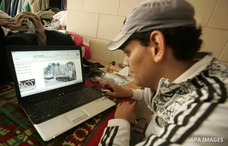 A Palestinian man looks at the computer to follow the hot events in Egypt, in Rafah, southern Gaza Strip on January 29, 2011. Protest demonstrations continued in central Cairo after the government-ordered overnight curfe...