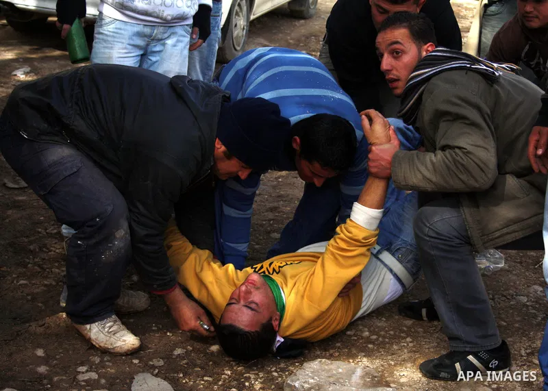 Palestinians carry a wounded youth after clashes with Israeli soldiers started during the funeral of Palestinian Youssef Ekhaleil in the West Bank village of Beit Omar, near Hebron, Saturday, Jan. 29, 2011. Ekhaleil died...