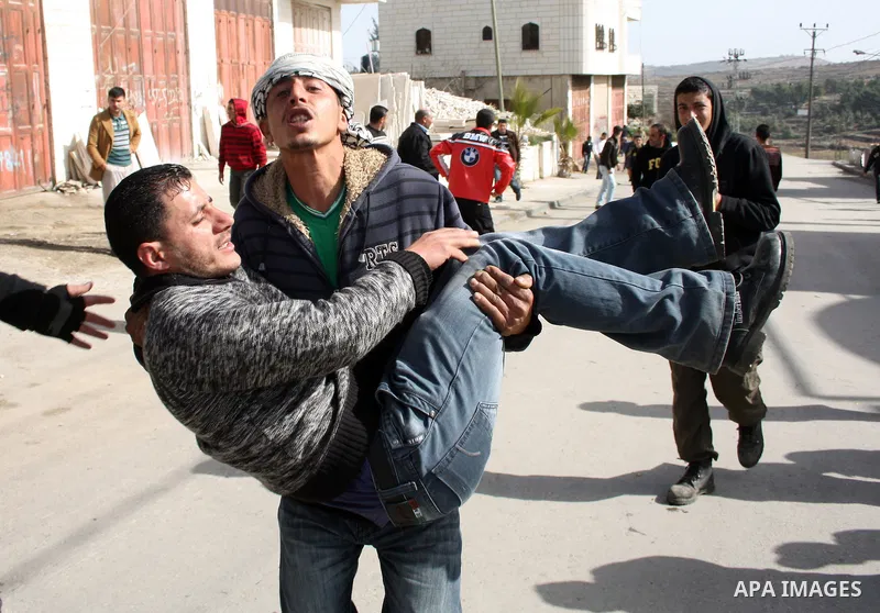 Palestinians carry a wounded youth after clashes with Israeli soldiers started during the funeral of Palestinian Youssef Ekhaleil in the West Bank village of Beit Omar, near Hebron, Saturday, Jan. 29, 2011. Ekhaleil died...