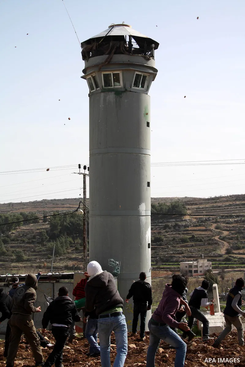 Palestinians throw stones towards an Israeli army tower after clashes started during the funeral of Youssef Ekhaleil in the West Bank village of Beit Omar, near Hebron, Saturday, Jan. 29, 2011. Ekhaleil died of his wound...