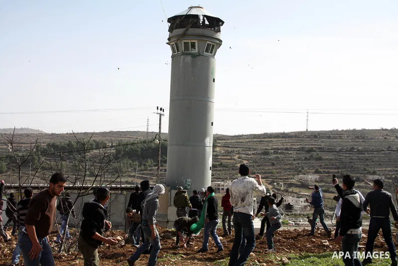 Palestinians throw stones towards an Israeli army tower after clashes started during the funeral of Youssef Ekhaleil in the West Bank village of Beit Omar, near Hebron, Saturday, Jan. 29, 2011. Ekhaleil died of his wound...