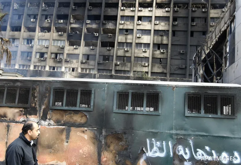 An Egyptian man passes by a charred building in Cairo, Egypt, Sunday, Jan. 30, 2011. Photo by STR
