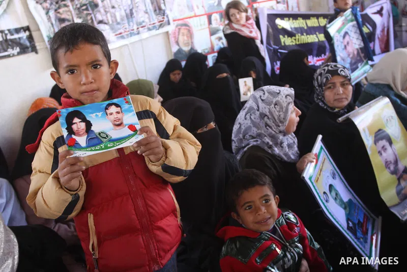 Palestinian women and children hold pictures of jailed relatives during a protest calling for the release of Palestinian prisoners from Israeli jails at the Red Cross office in Gaza City on Jan. 31, 2011. Photo by Mohamm...