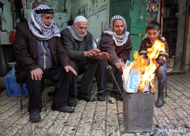 Palestinian men sit around a fire in the market during heavy rains in the old city of West Bank city of Hebron January 31, 20111. Photo by Najeh Hashlamoun