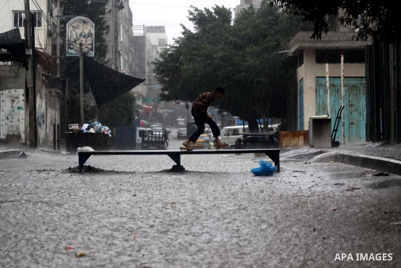 Palestinians walk in a rain flooded street at the Shati refugee camp in Gaza City, Tuesday, Feb. 1 , 2011.. Photo by Mohammed Asad
