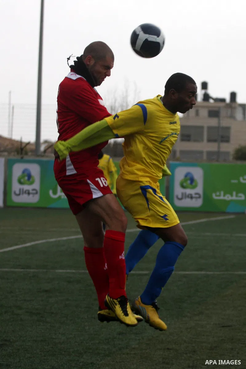 Palestinians play a football match between Tulkarem Center club (yellow) and Al-Beraeh Foundation club (red) in the occupied West Bank on Feb. 1,2011. Photo by Issam Rimawi