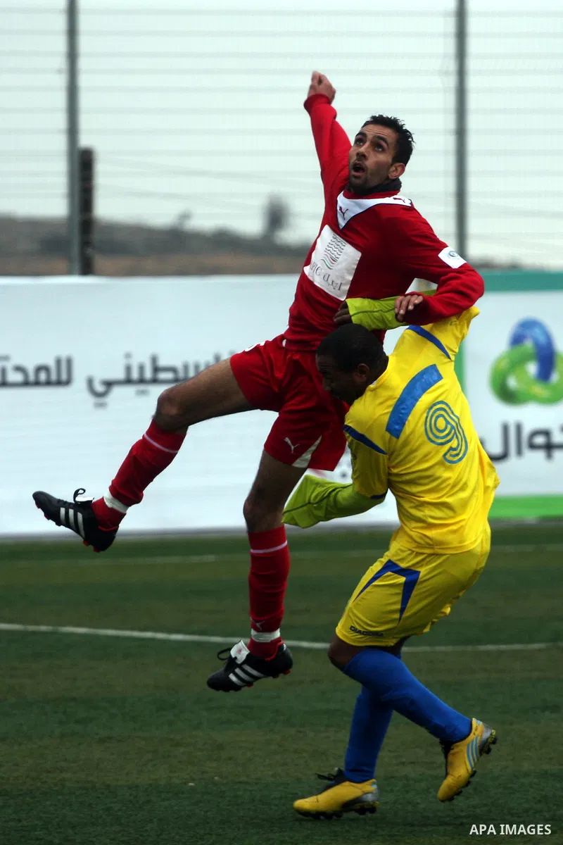 Palestinians play a football match between Tulkarem Center club (yellow) and Al-Beraeh Foundation club (red) in the occupied West Bank on Feb. 1,2011. Photo by Issam Rimawi