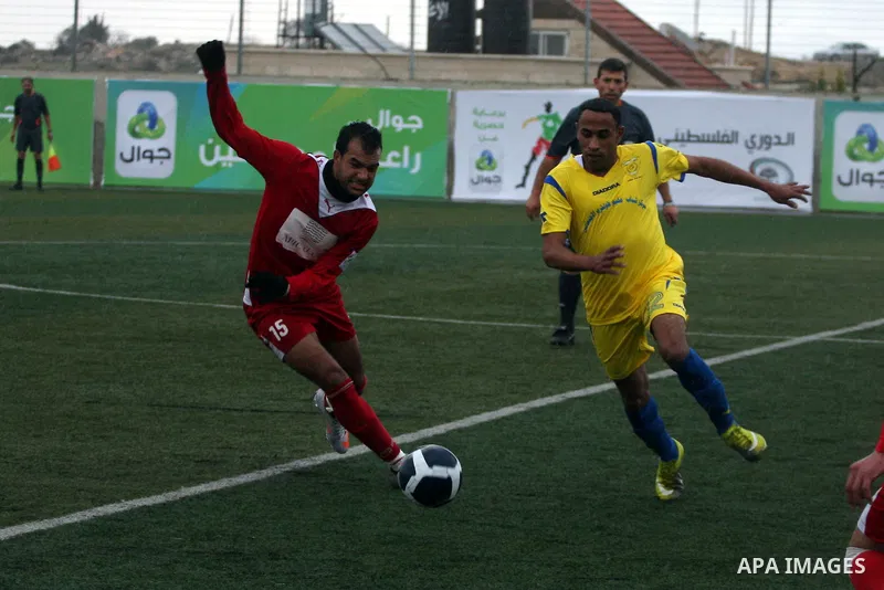 Palestinians play a football match between Tulkarem Center club (yellow) and Al-Beraeh Foundation club (red) in the occupied West Bank on Feb. 1,2011. Photo by Issam Rimawi