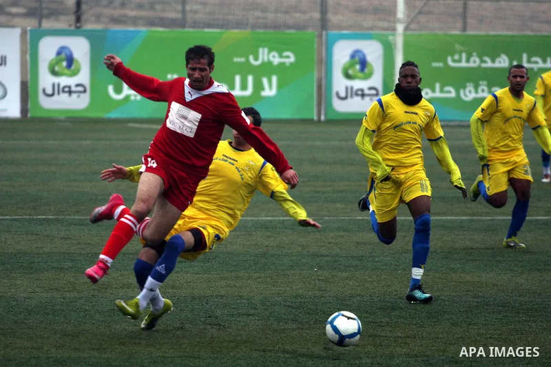Palestinians play a football match between Tulkarem Center club (yellow) and Al-Beraeh Foundation club (red) in the occupied West Bank on Feb. 1,2011. Photo by Issam Rimawi
