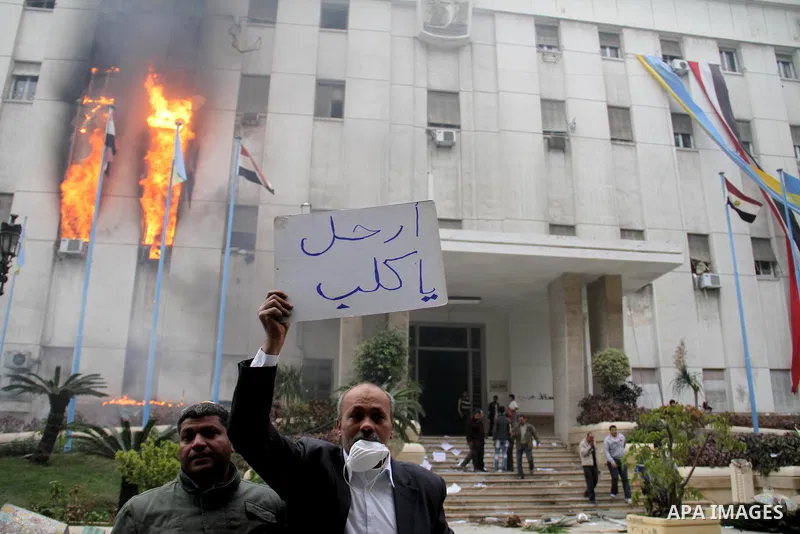 Egyptian protesters stand in front of burning building during a anti-government protesters demonstrate against president Hosni Mubarak regime in Alexandria, Egypt, Jan. 28, 2011. Egyptian President Hosni Mubarak defied a...