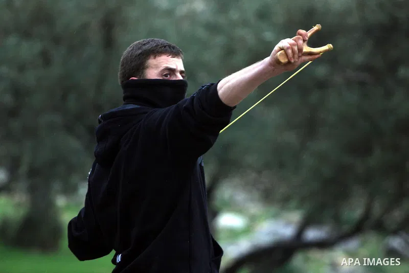A Palestinian youth hurls stones towards Israeli sildiers during a protest in the village of Bilin near Ramallah on Feb. 4, 2011. Photo by Issam Rimawi
