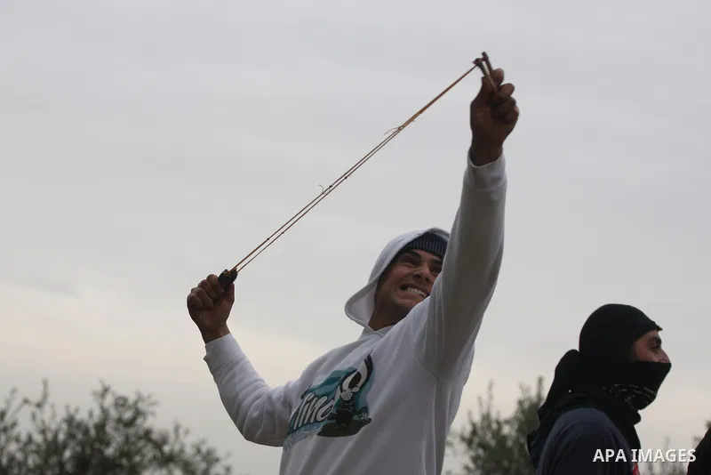 A Palestinian youth hurls stones towards Israeli sildiers during a protest in the village of Bilin near Ramallah on Feb. 4, 2011. Photo by Issam Rimawi