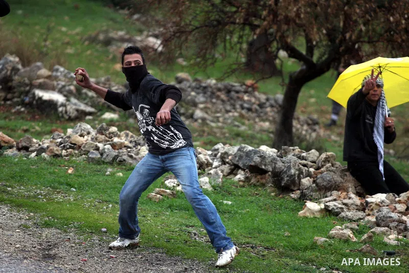 A Palestinian youth hurls stones towards Israeli sildiers during a protest in the village of Bilin near Ramallah on Feb. 4, 2011. Photo by Issam Rimawi