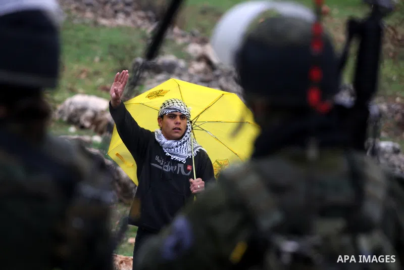 A Palestinian protester holds an umbrella during a protest against Israel's separation barrier in the West Bank village of Bilin near Ramallah, Friday, Feb 4, 2011. Photo by Issam Rimawi