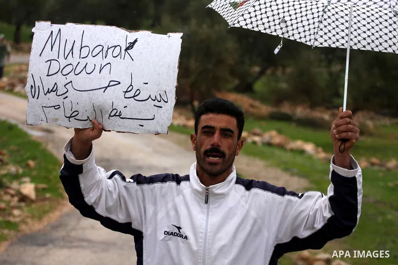 A Palestinian protester holds a banner in support of the Egyptian people during a protest against Israel's separation barrier in the West Bank village of Bilin near Ramallah, Friday, Feb 4, 2011. Photo by Issam Rimawi