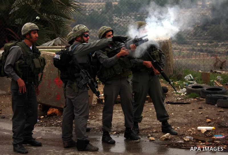 An Israeli soldier fires a tear gas towards Palestinian protesters during a demonstration against the Israeli controversial separation barrier in the West Bank village of Beit Omar, near Hebron, 05 February 2011. Israel...