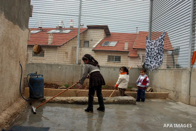 Palestinians are seen in the fenced in back yard of the Sabri Gareeb family home which is situated in the center of the Givon Ha Hadasha Jewish settlement just south of Ramallah in the Israeli occupied West Bank on Febru...
