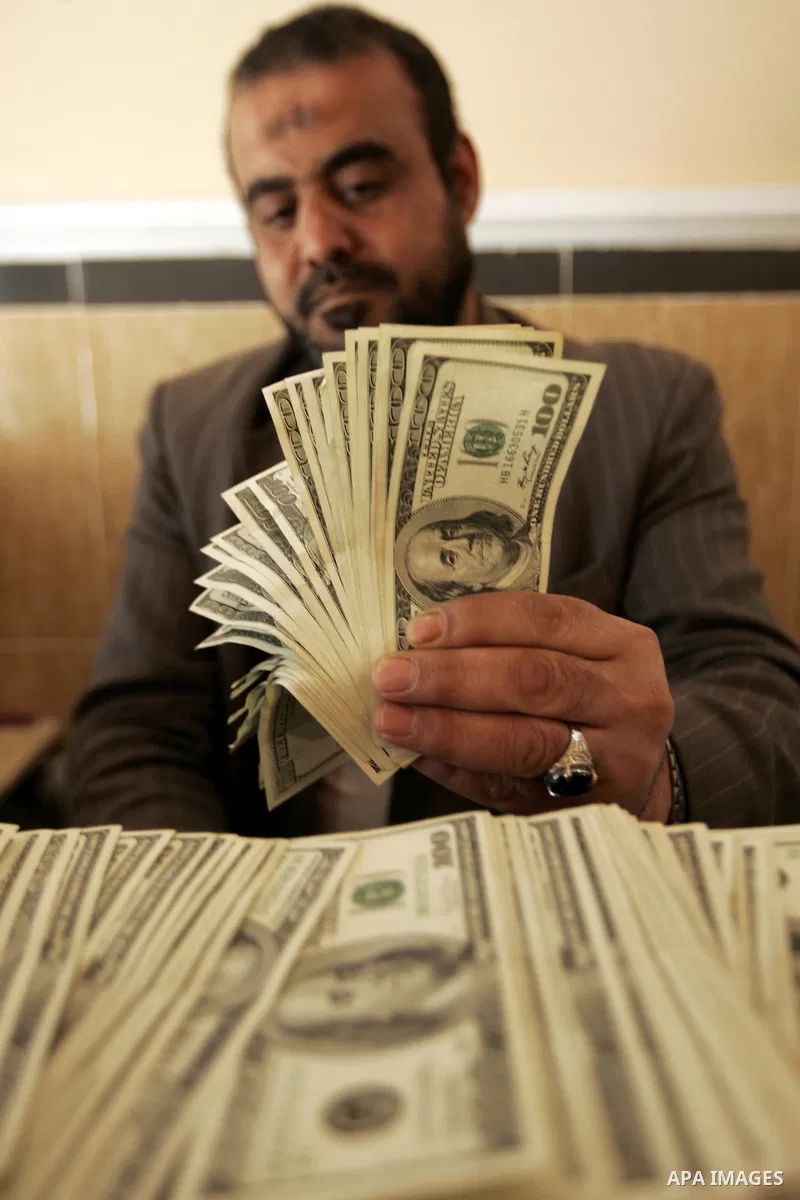 A Palestinian man displays money at his exchanges currency shop in the southern Gaza Strip town of Rafah on Feb. 2011. Photo by Abed Rahim Khatib