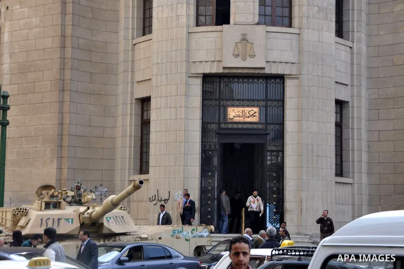 Egyptians walk in front of a court in Cairo, Egypt, Tuesday, Feb. 8, 2011. Protesters appear to have settled in for a long standoff, turning Tahrir Square into a makeshift village with tens of thousands coming every day,...