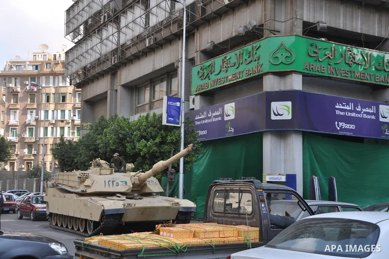 Egyptian tank is seen near a bank in Cairo, Egypt, Tuesday, Feb. 8, 2011. Protesters appear to have settled in for a long standoff, turning Tahrir Square into a makeshift village with tens of thousands coming every day,...