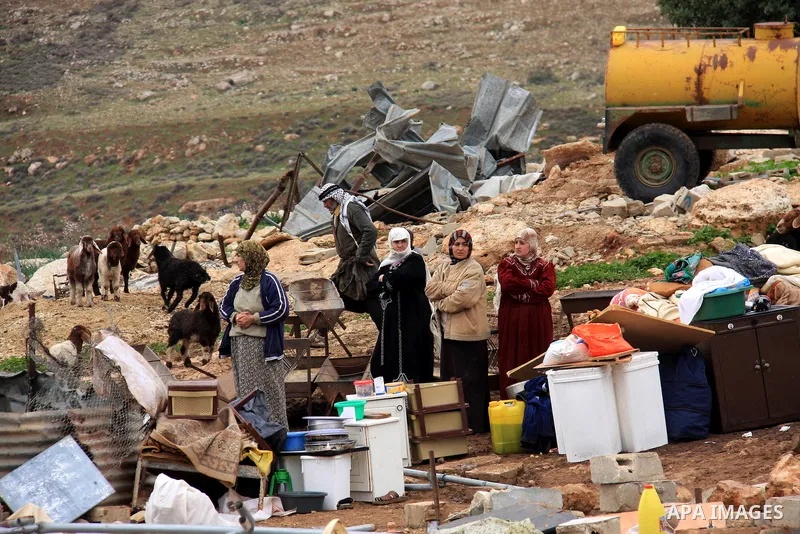 Palestinians stand next to their belongings after the Civil Administration demolished constructions in the village of Khirbet Tana near the West Bank city of Nablus, Wednesday, Feb. 9, 2011. According to Palestinian witn...