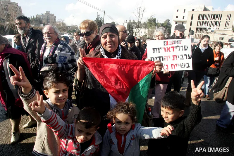 Palestinians, Israelis and foreign activists hold signs during a protest to show solidarity with Palestinian families against a Jewish settlement in the Sheikh Jarrah neighbourhood in East Jerusalem on Feb. 11, 2011. Pho...