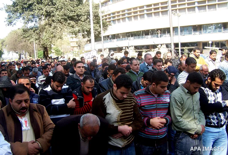 Anti-government protesters pray in front the state television building in Cairo, Egypt, Friday, Feb. 11, 2011. Mubarak has refused to step down or leave the country, and instead handed his administrative powers to his vi...