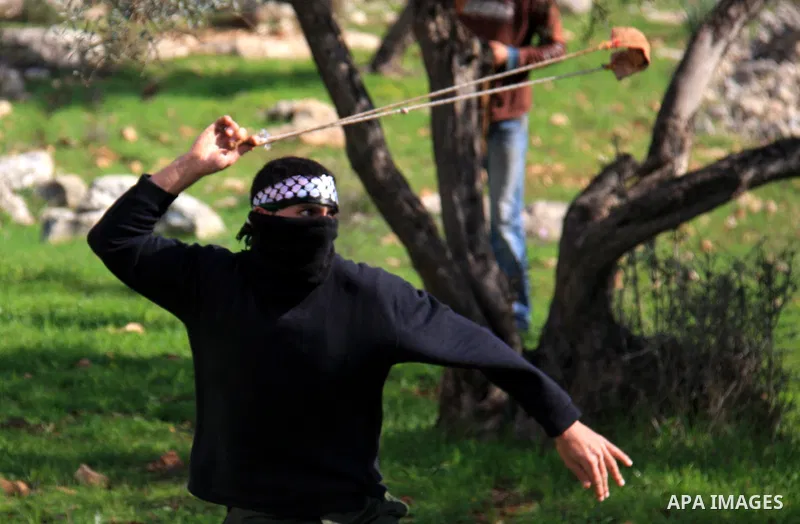 A Palestinian youth uses a sling to hurl stones towards Israeli soldiers during the weekly demonstration against Israel's separation barrier in the West Bank village of Bilin near Ramallah, Friday, Feb. 11, 2011. Photo b...
