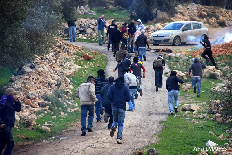 Palestinian youths run for cover from tear gas canisters fired by Israeli soldiers during the weekly demonstration against Israel's separation barrier in the West Bank village of Bilin near Ramallah, Friday, Feb. 11, 201...