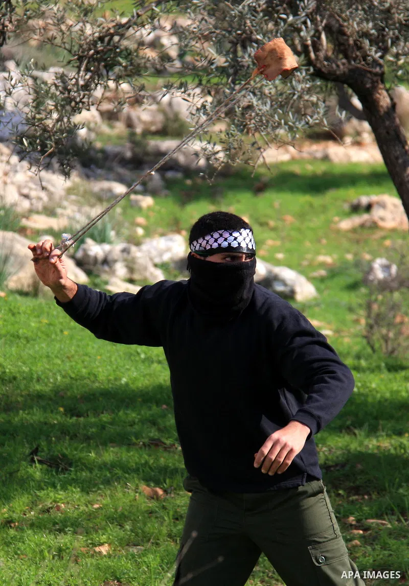 A Palestinian youth uses a sling to hurl stones towards Israeli soldiers during the weekly demonstration against Israel's separation barrier in the West Bank village of Bilin near Ramallah, Friday, Feb. 11, 2011. Photo b...