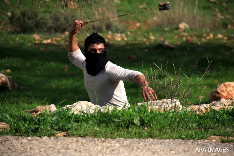 A Palestinian youth uses a sling to hurl stones towards Israeli soldiers during the weekly demonstration against Israel's separation barrier in the West Bank village of Bilin near Ramallah, Friday, Feb. 11, 2011. Photo b...