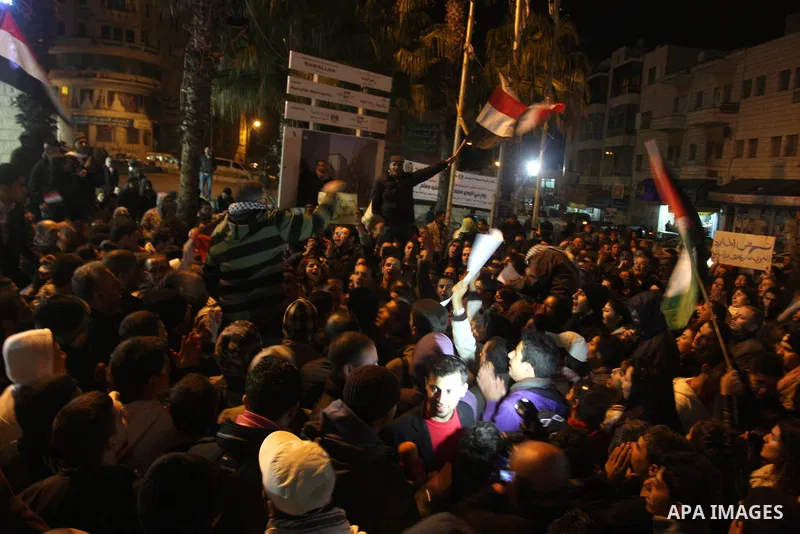 Palestinians celebrate the news of the resignation of President Hosni Mubarak, who handed control of the country to the military, at night in the West Bank city of Ramallah, Friday, Feb. 11, 2011. Photo by Issam Rimawi