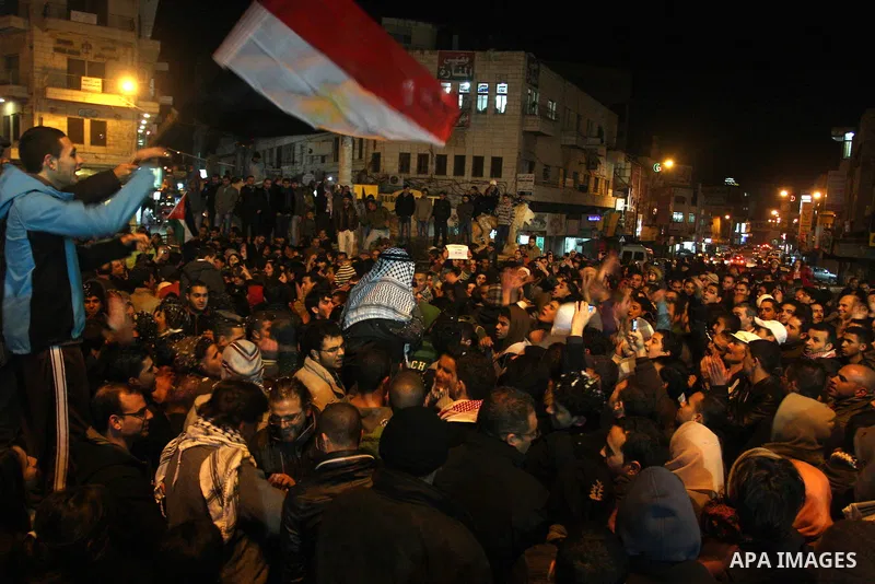 Palestinians celebrate the news of the resignation of President Hosni Mubarak, who handed control of the country to the military, at night in the West Bank city of Ramallah, Friday, Feb. 11, 2011. Photo by Issam Rimawi