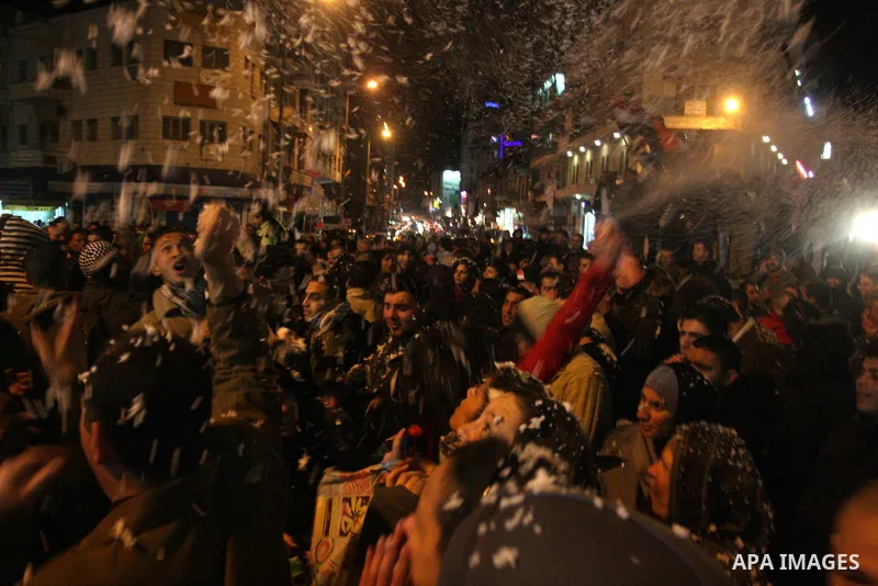 Palestinians celebrate the news of the resignation of President Hosni Mubarak, who handed control of the country to the military, at night in the West Bank city of Ramallah, Friday, Feb. 11, 2011. Photo by Issam Rimawi