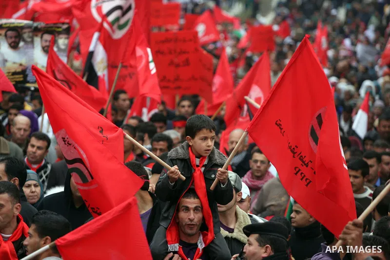 Palestinians wave red flags during a demonstration marking the 29th anniversary of the Palestinian People's Party, a socialist political party, in the West Bank city of Ramallah, Saturday, Feb. 12, 2011. Photo by Issam R...