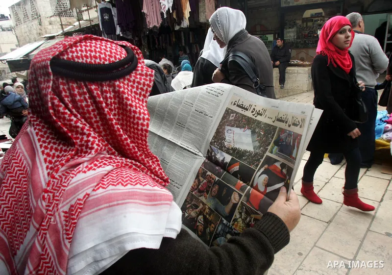 A Palestinian man reads a local newspaper as he looks at the Egypt news at the main market in jerusalem's old city on Feb. 12,2011. Photo by Mahfouz Abu Turk