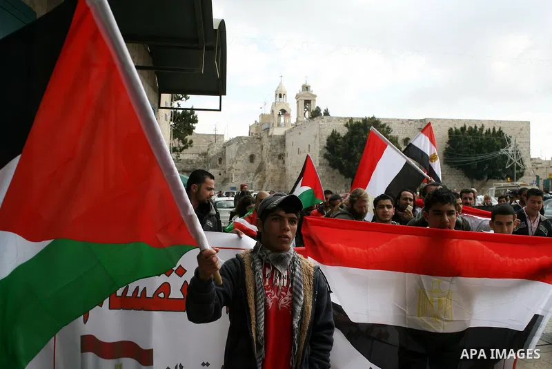 Palestinians hold Egypt and Palestine flags during a protest outside the Church of the Nativity in the West Bank town of Bethlehem 13 February 2011, to show support for the people of Egypt. Photo by Najeh Hashlamoun