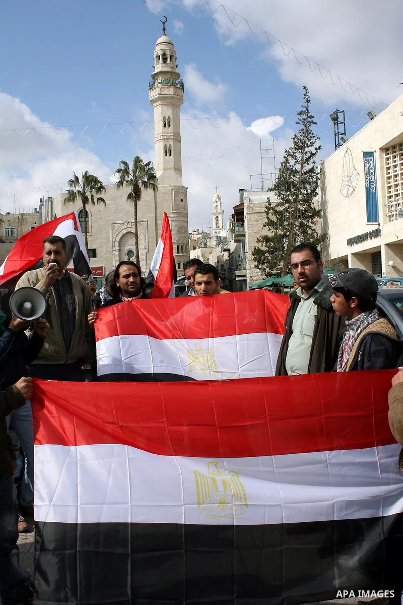 Palestinians hold Egypt and Palestine flags during a protest outside the Church of the Nativity in the West Bank town of Bethlehem 13 February 2011, to show support for the people of Egypt. Photo by Najeh Hashlamoun
