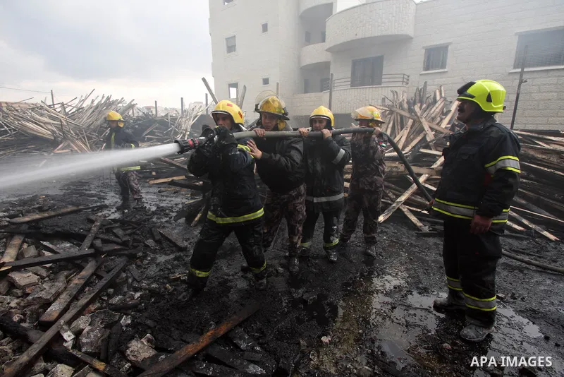 Palestinian civil defense forces try to stop fire burning in carpentry workshop and a factory for plastic materials, in the area of Doha, near the biblical town of Bethlehem, on February 13, 2011. Photo by Najeh Hashlamo...
