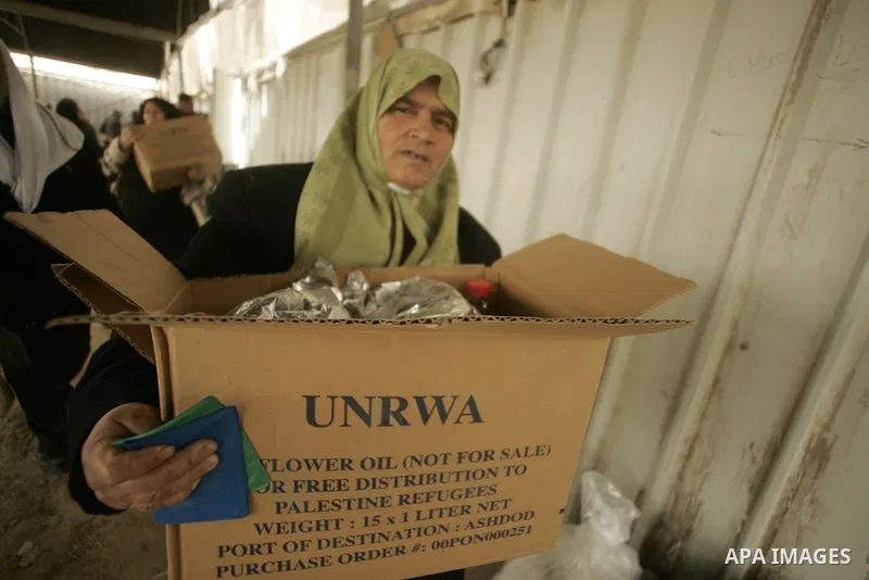 A Palestinian woman receives food aids from the United Nations Relief and Works Agency (UNRWA) at the Rafah refugee camp, in the southern Gaza Strip on February 16, 2011. Accused the owners of destroyed houses and Relief...