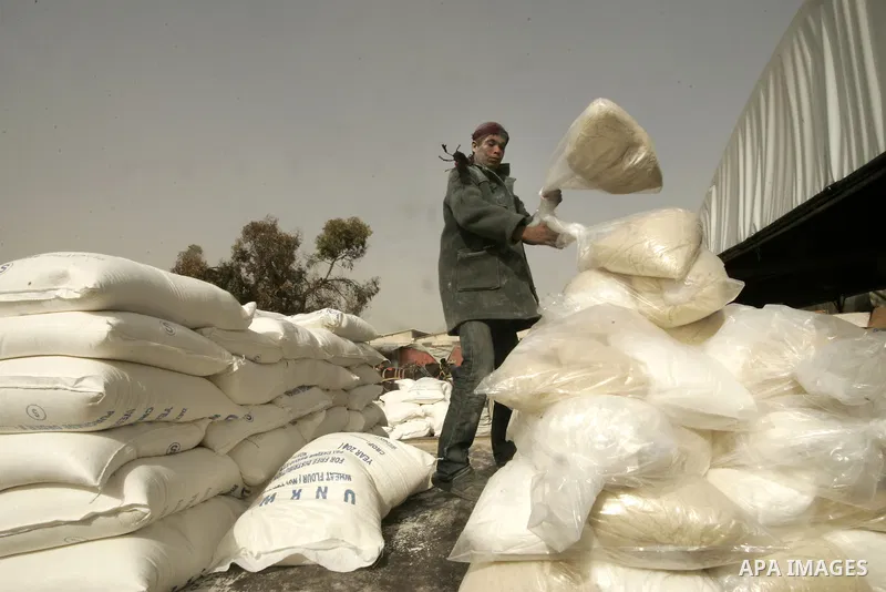 A Palestinian youth receives food aids from the United Nations Relief and Works Agency (UNRWA) at the Rafah refugee camp, in the southern Gaza Strip on February 16, 2011. Accused the owners of destroyed houses that the R...