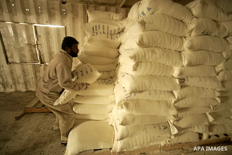 Palestinian man carries a bag with wheat flour as they receive food aids from the United Nations Relief and Works Agency (UNRWA) at the Rafah refugee camp, in the southern Gaza Strip on February 16, 2011. Accused the own...