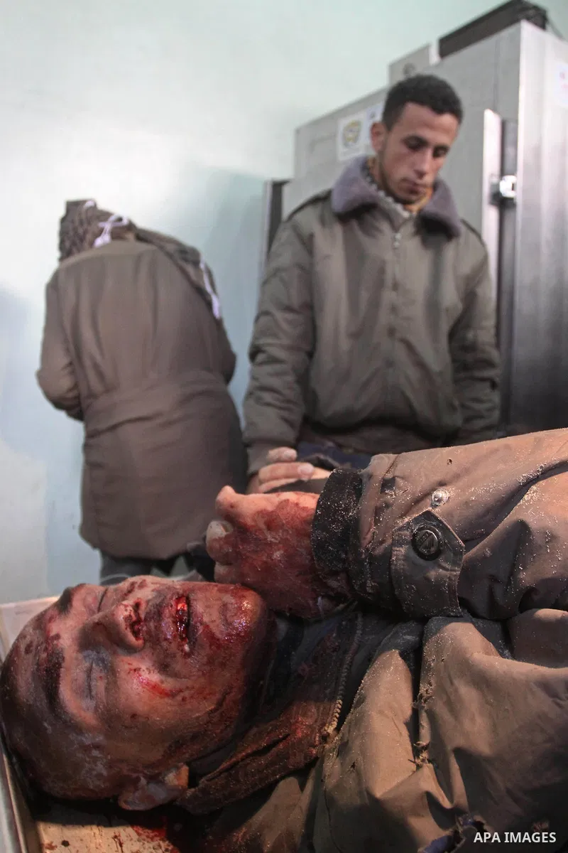 Palestinians stand next to the body of one of the three killed Palestinians, at the morgue in Kamal Adwan hospital in the town of Beit Lahiya, northern Gaza Strip, on Feb. 17, 2011. Three Palestinian fishermen were slain...
