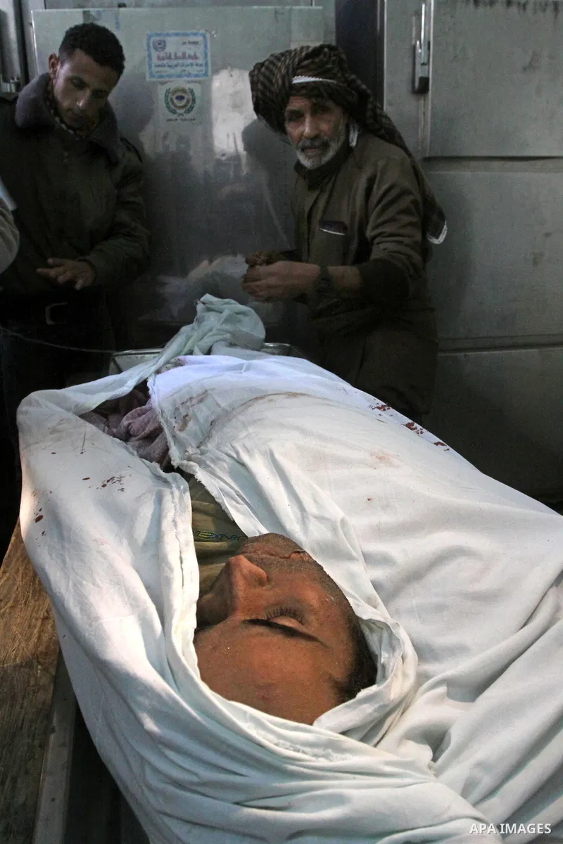 Palestinians look at the body of one of the three killed Palestinians, at the morgue in Kamal Adwan hospital in the town of Beit Lahiya, northern Gaza Strip, on Feb. 17, 2011. Three Palestinian fishermen were slain on ea...